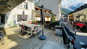 Un terrazzo in legno con posti a sedere all'aperto e vista su una catena montuosa.