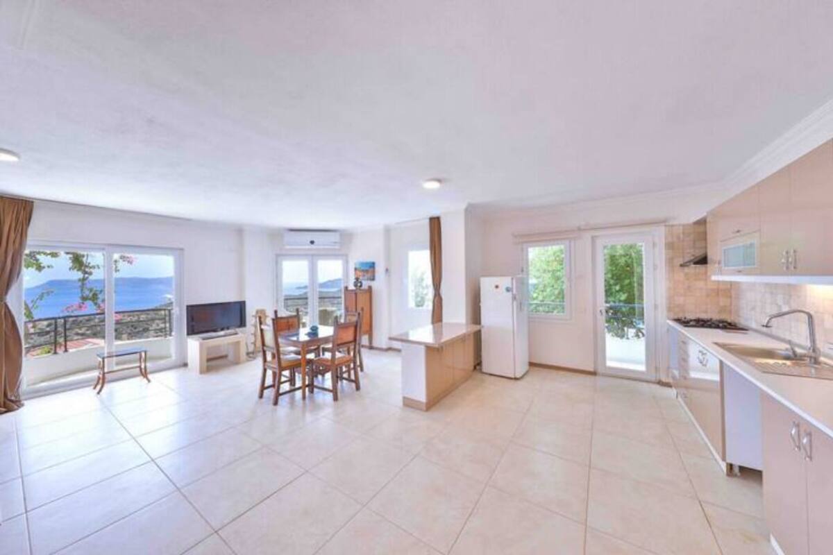 Una cocina amplia con comedor, ventanas grandes y vistas al mar.