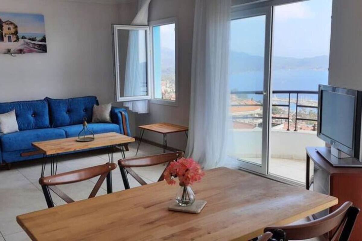 Una sala de estar moderna con un sofá azul, una mesa de comedor de madera y un televisor sobre un mueble.