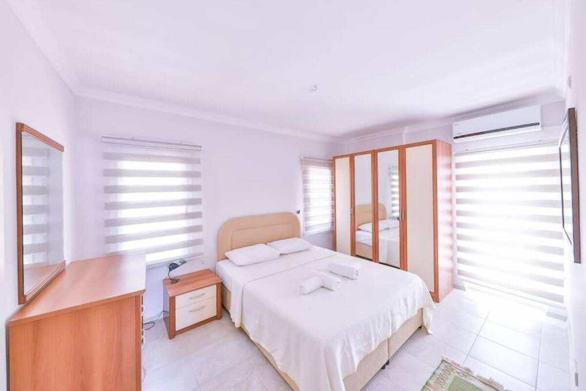 Un dormitorio moderno con cama, mesita de noche y espejo.