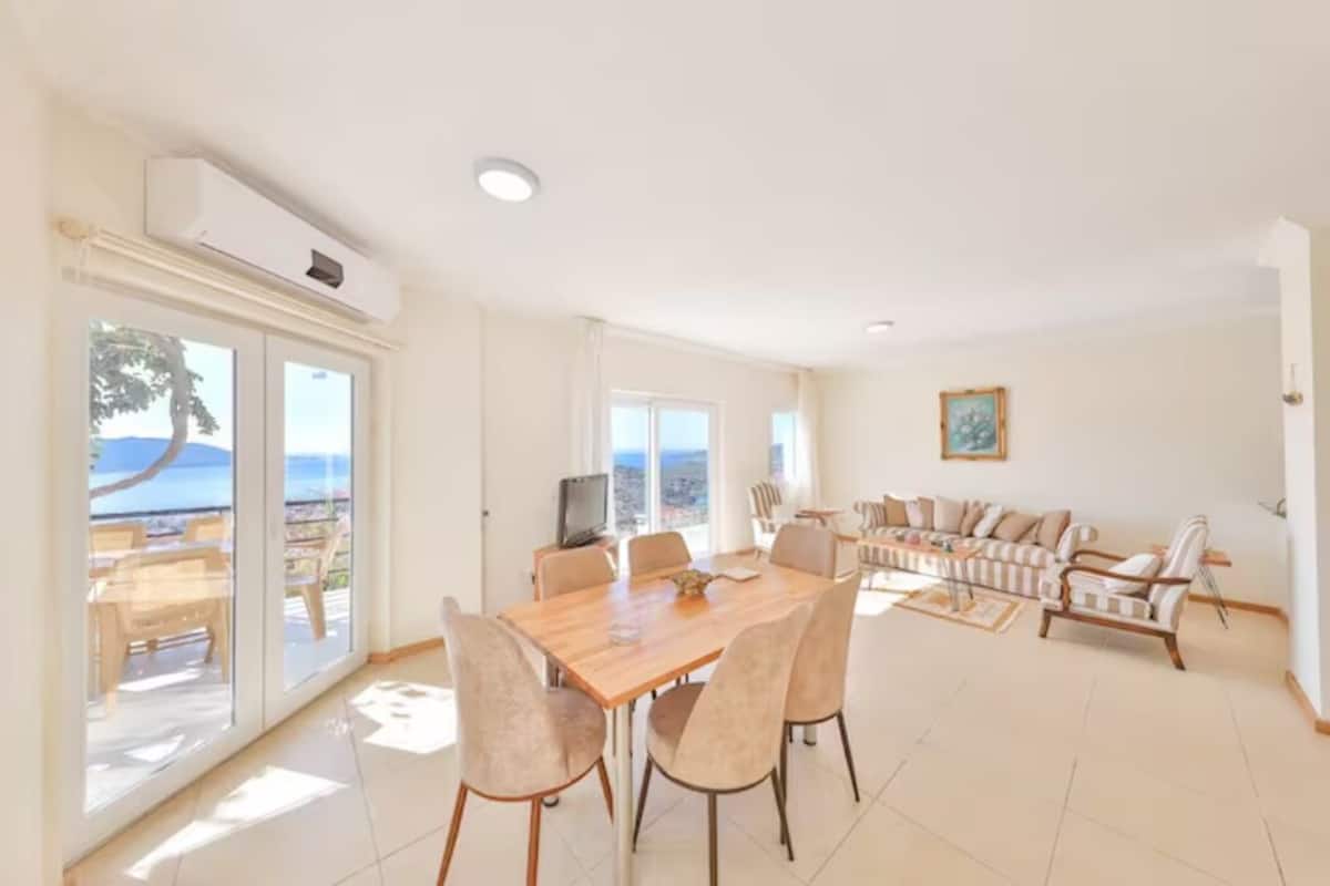 Amplia sala de estar con una gran mesa de comedor de madera, asientos cómodos y un televisor.