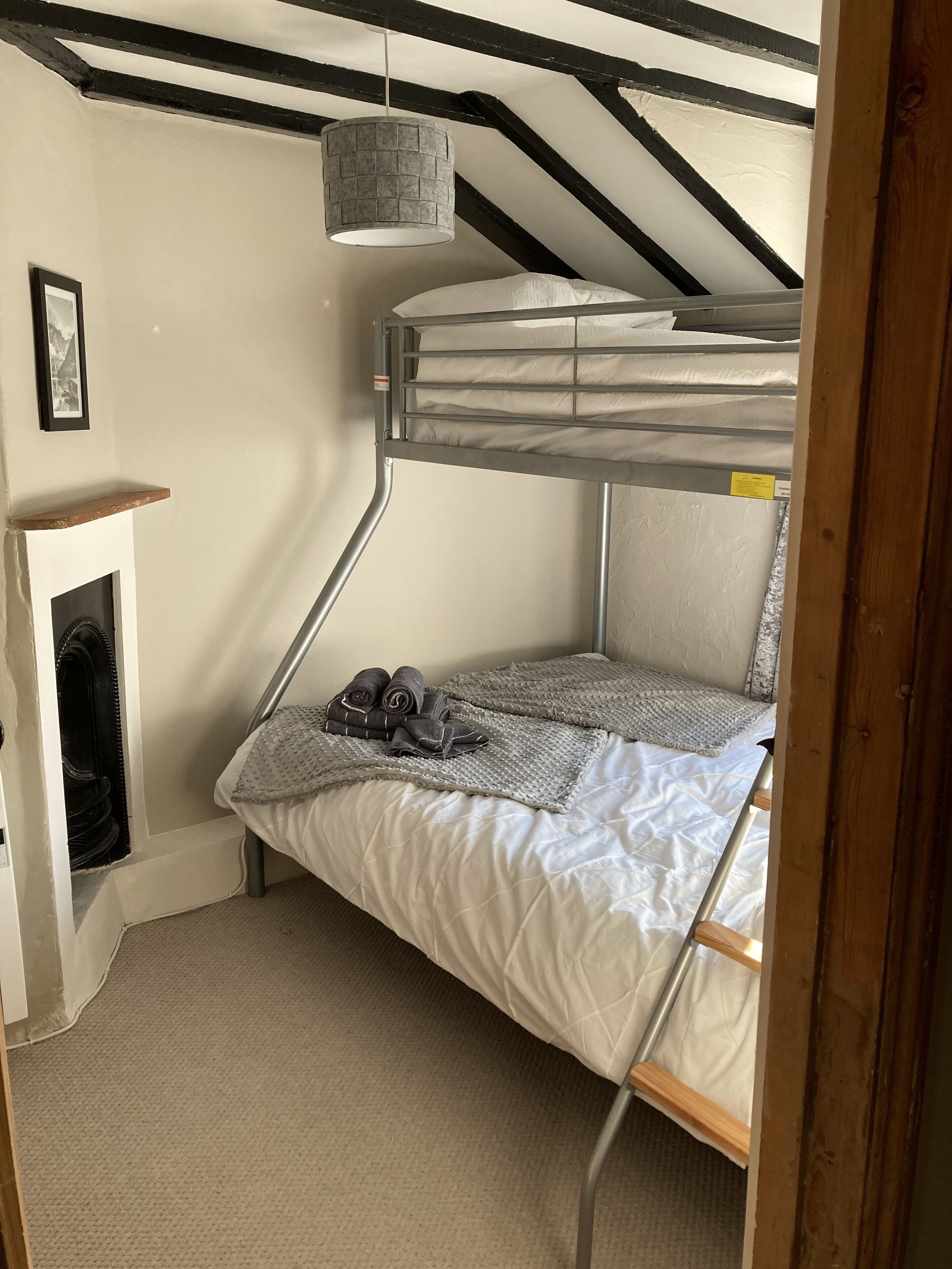 Een stapelbed met hoofdbord, een klein plankje en een hangende lamp.