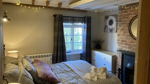 Ein gemütliches Schlafzimmer mit einem großen Bett, einem Kamin und einem Vorhangfenster.