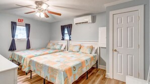 A bedroom with two beds, an exit sign, a ceiling fan, and a door. - Newly Remodeled Condo - Steps to Beach & Boardwalk (Ocean City)