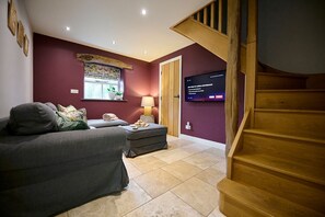 Relax in this stylish living room with a sofa, table, and TV, plus a staircase leading to an upper level.