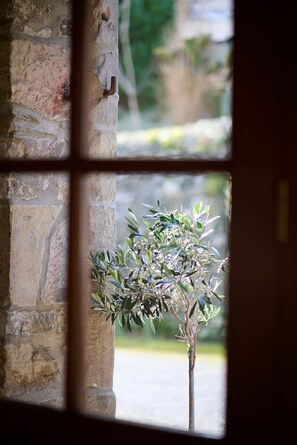 Enjoy a serene view from this cozy room, featuring a window with a small plant and a stone wall.