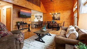 A cozy cabin interior with a wooden ceiling, a dining area, and a living room with a sofa and a coffee table. - Incredible Mountain Views Near Dtown Gatlinburg! (Gatlinburg)