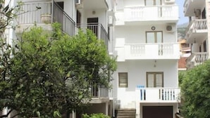 A residential building with multiple balconies, a central staircase, and a paved pathway. - NIR Apartments Budva  (Budva)