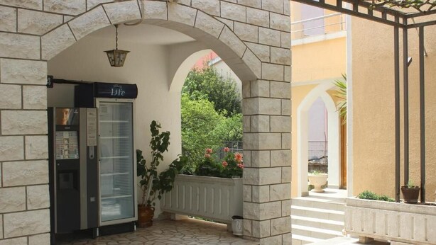 A hotel entrance with a reception desk, a glass door, and a stone archway. - NIR Apartments Budva  (Budva)