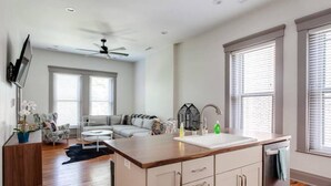 Una cocina moderna con una isla central, un área de comedor con sofá y un ventilador de techo.