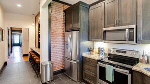 Una cocina moderna con electrodomésticos de acero inoxidable, armarios de madera oscura y una pared de ladrillo decorativa.