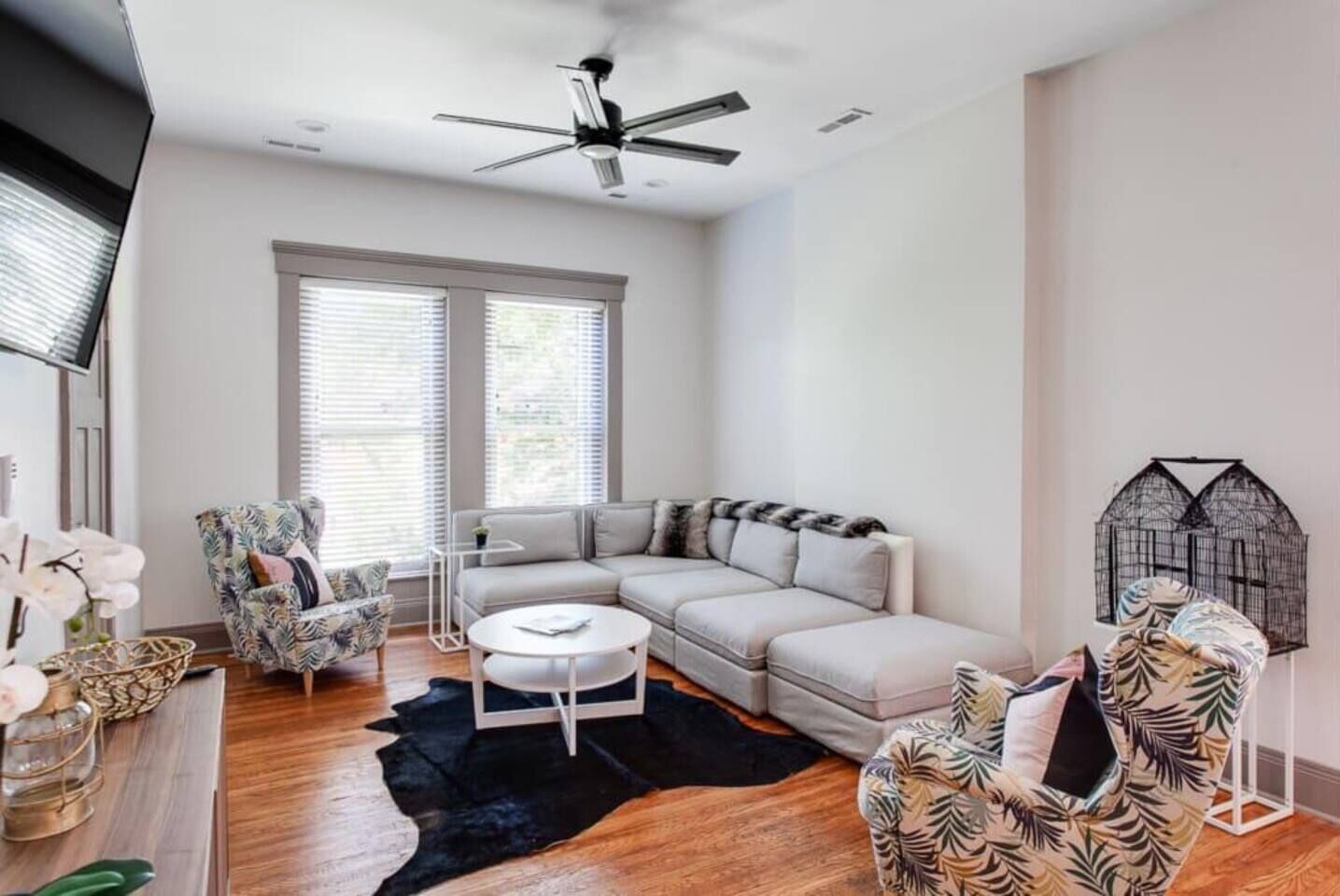 A modern living room with a sectional sofa, a round coffee table, and a ceiling fan.