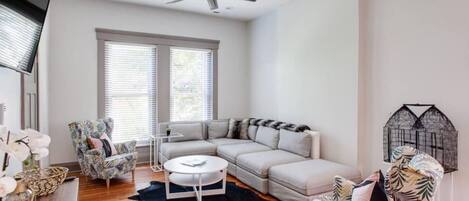 A modern living room with a sectional sofa, a round coffee table, and a ceiling fan.