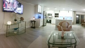 A spacious living area with a glass coffee table, a sofa, and a TV mounted on the wall. - Relax by the sea! Three bedroom home with pool awaits you near Destin Beaches. (Fort Walton Beach)