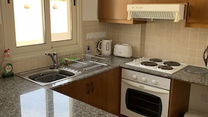 Une cuisine dotée de plans de travail en granit, d’un four encastré, d’une cuisinière à gaz, d’un grille-pain et d’une fenêtre donnant sur l’extérieur.