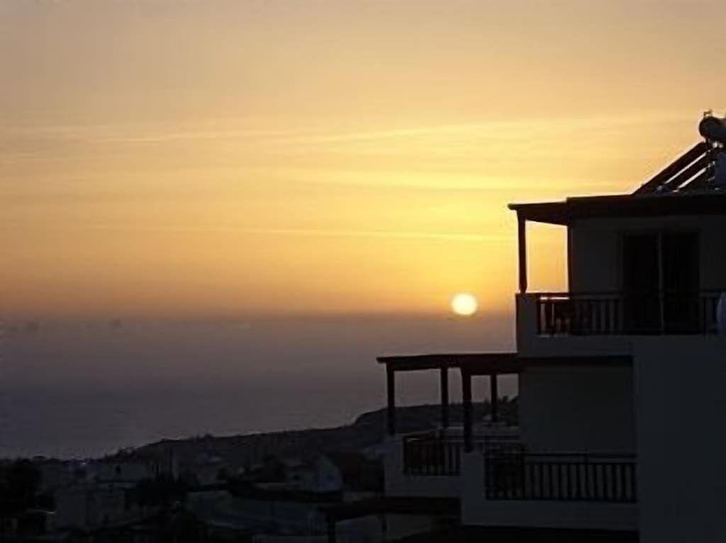 Ein Gebäude mit einem Balkon, der auf einen Sonnenuntergang blickt.