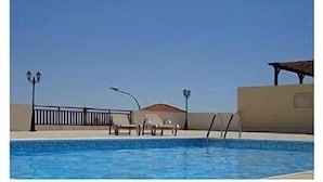A swimming pool with lounge chairs and a pergola. - Amazing panoramic ocean views, large sunny terrace. (Peyia)