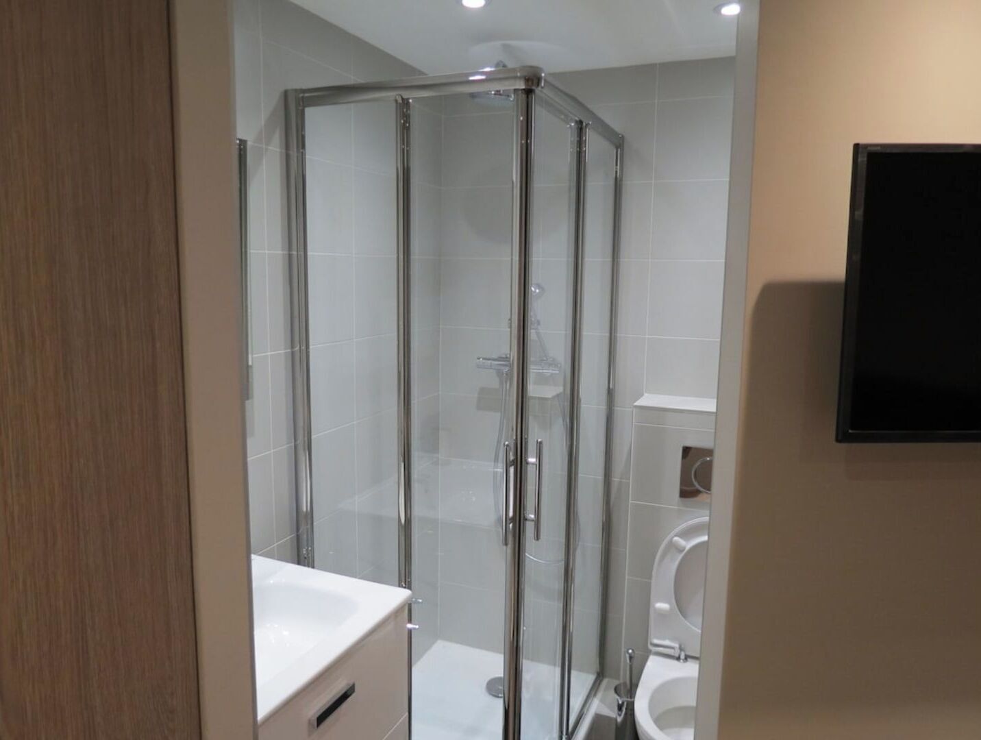 Un baño moderno con cabina de ducha de vidrio, un lavabo blanco y un inodoro.