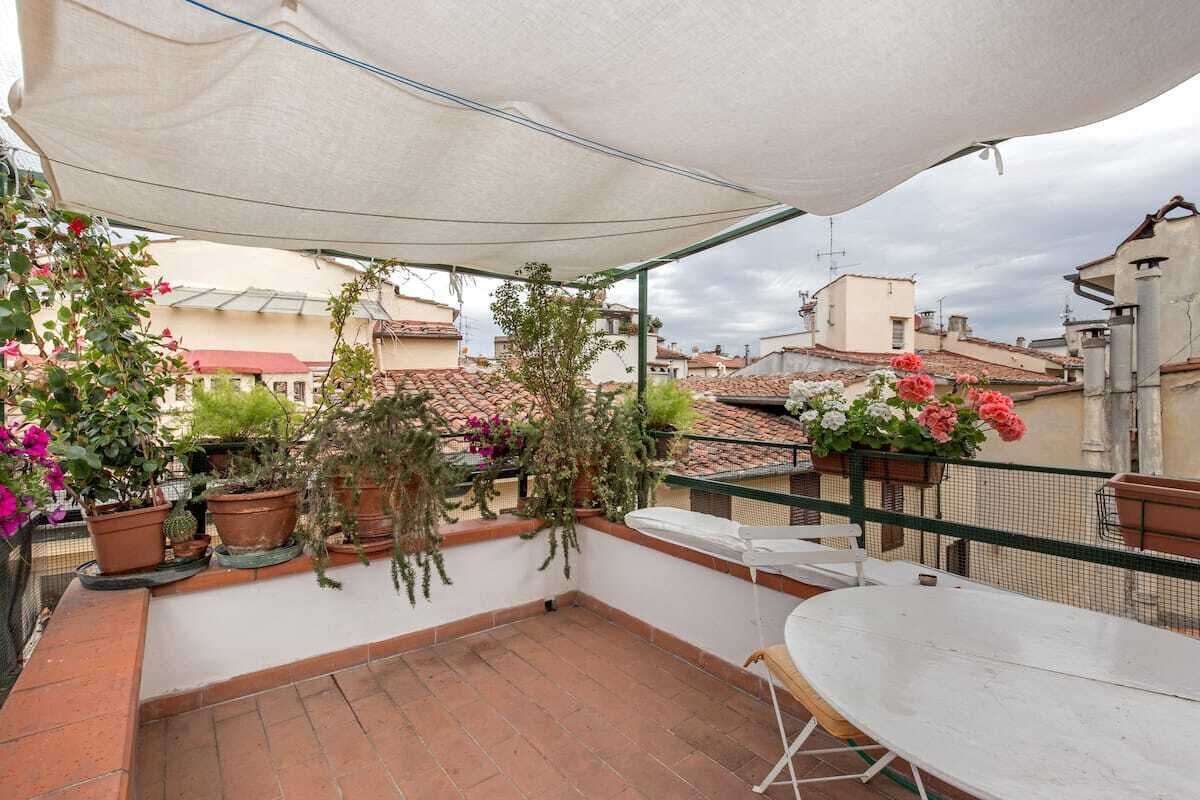 A rooftop terrace with potted plants and a table.