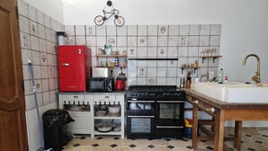 A compact kitchen with a red refrigerator, a microwave, a stove, and a sink. - The Wine Press (Turquant)