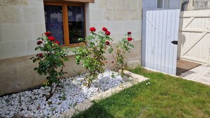 A building with a window and a white door, surrounded by gravel and grass. - The Wine Press (Turquant)