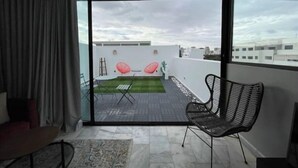 Een moderne woonkamer met een grote schuifpui naar een balkon met een kleine tuin en zithoek.