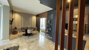 Een moderne woonkamer met een eethoek, een groot raam en een ingebouwde boekenkast.