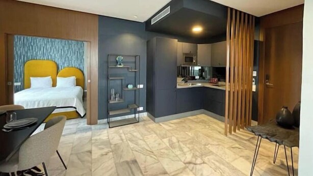 Een moderne hotelkamer met een bed, een zithoek, een keuken en een badkamer.