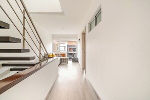 Un intérieur moderne avec un escalier, un espace de vie doté d’un canapé et une cuisine en arrière-plan.