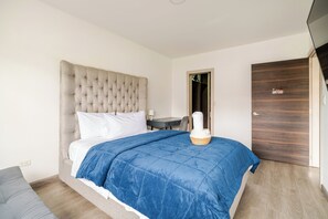 Une chambre à coucher avec un grand lit, une table de chevet, une chaise, une armoire et une porte.