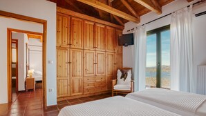 Camera da letto con due letti, un armadio in legno, TV e vista sulla spiaggia.