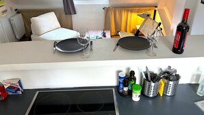 A kitchenette with a stove, a dining area with a table set for two, and a window with curtains. - Le Penthouse Picardie (Paris)