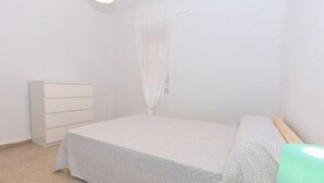 Ein Schlafzimmer mit einem Bett, einer Kommode und einem Vorhang.