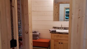 Un baño con paneles de madera, un lavamanos, un espejo y un banco.