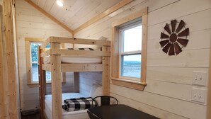 Una habitación de cabaña de madera con literas, una mesa y una ventana con vistas.