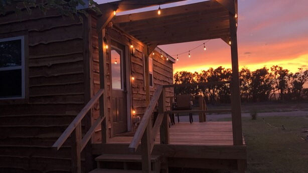 Una cabaña de madera con un porche, escalones y luces colgantes.