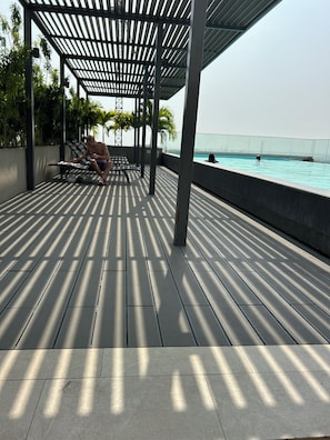 Un espace extérieur abrité comprenant une piscine, une terrasse en bois et des sièges.