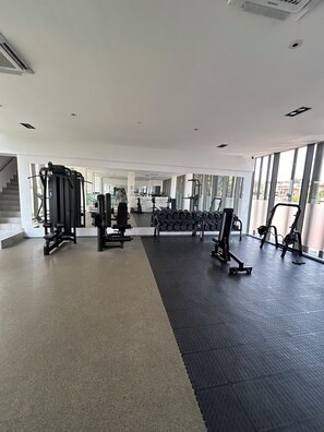 A gym with various exercise equipment, a dumbbell rack, and a staircase leading to another level. - Luxurious One bedroom Apartment at The Lennox Airport Residential Accra (Accra)