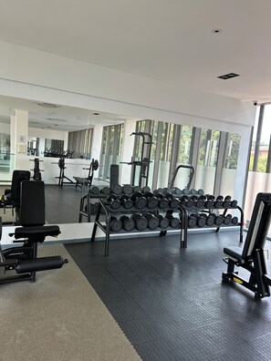 Une salle de sport équipée de matériel d’exercice, dotée d’un miroir et de grandes fenêtres.