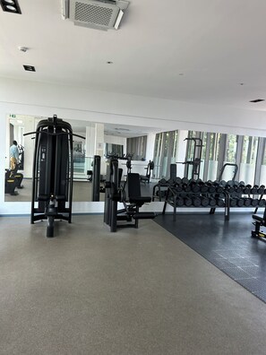 A gym with exercise equipment, a mirror, and a rack of dumbbells. - Luxurious One bedroom Apartment at The Lennox Airport Residential Accra (Accra)