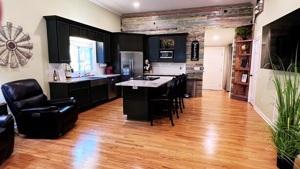 A modern kitchen with dark cabinetry, a central island, and a dining area. - Home Near USC, Perfect for Families & Graduations - Deja Blues  (West Columbia)