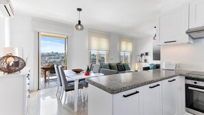 Una cocina moderna con armarios blancos, encimera de granito y horno empotrado.