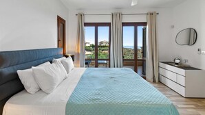 A bedroom with a bed, a nightstand, a dresser, a mirror, and a balcony with a view. - Villa TA01 Ouranos - Three Bedroom Villa, Sleeps 6 (Kouklia)