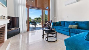 Een moderne woonkamer met een blauwe bank, een ronde salontafel en een televisie.