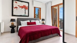 Een slaapkamer met een groot bed, twee nachtkastjes met lampen, een schilderij aan de muur en een balkon met een deur.