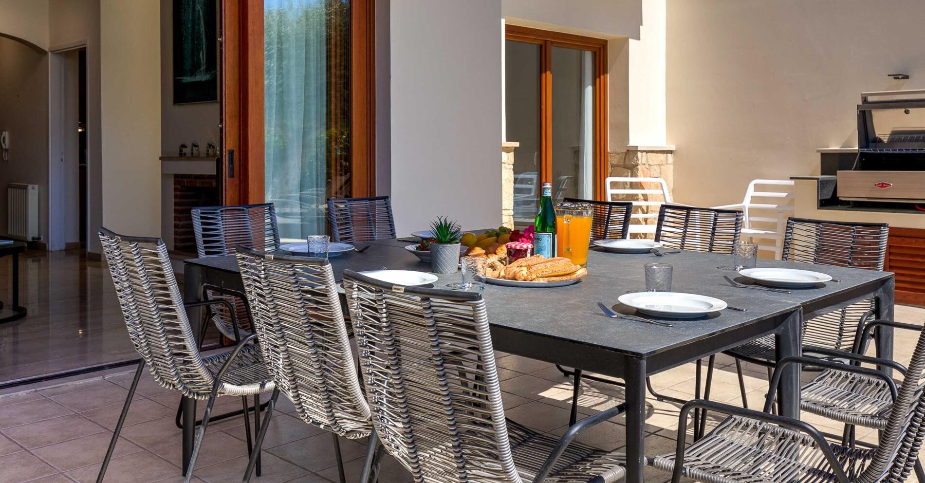 Un coin repas avec une table dressée pour quatre personnes, entourée de chaises en osier.