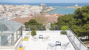 A rooftop terrace with outdoor seating, a view of the sea, and a lighthouse in the distance. - Dimora Cummà Marì (Vieste)