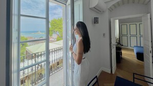 A room with a large sliding glass door leading to a balcony with a view of the sea and buildings. - Dimora Cummà Marì (Vieste)