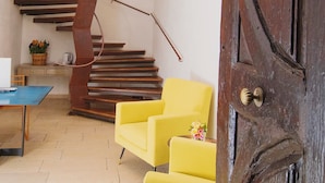 A staircase with wooden steps and a metal railing, a yellow armchair, and a wooden door with a brass handle. - Dimora Cummà Marì (Vieste)