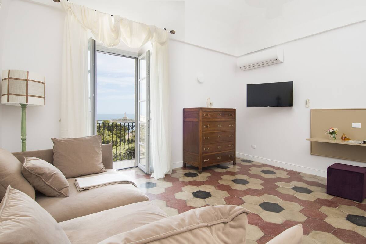A room with a sofa, a wooden dresser, a television, and a patterned floor.